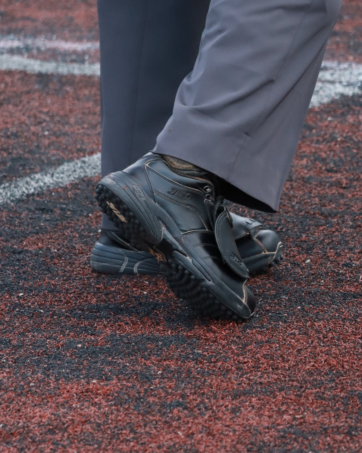 Person wearing black shoes and gray pants standing on a red and green surface